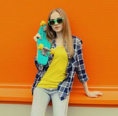 Stylish young woman with skateboard, modern teenage girl posing on city street