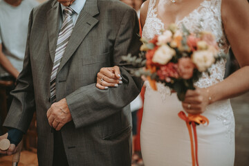 La mariée qui tient le bras de son grand-père pour l'entrée à l'église le jour de son mariage