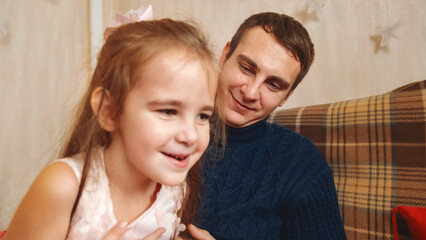 Father and daughter playing together in front of the Christmas tree