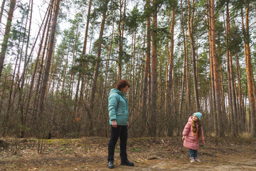 Grandmother with granddaughter walking in nature in the forest