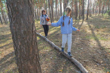 Grandmother and granddaughter walking with a ball in the forest in sunny day.