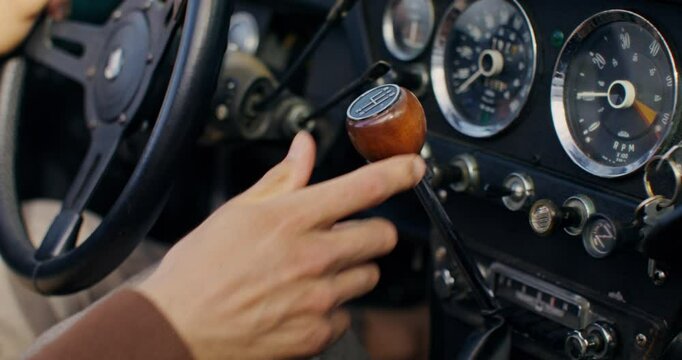 A man shifts gears in a retro car. Close-up of his hand, unrecognizable person