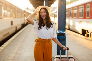 European lady waiting her train at the railway station, walking with suitcase, starting her summer...