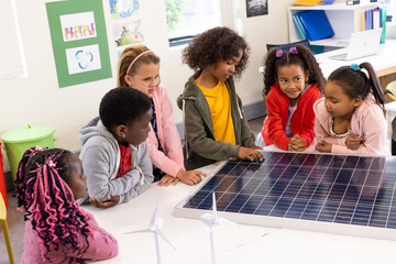 Diverse children in school exploring solar panel technology, learning about renewable energy