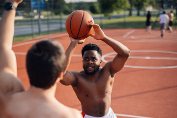 Young athletic man shooting a basketball on outdoor court