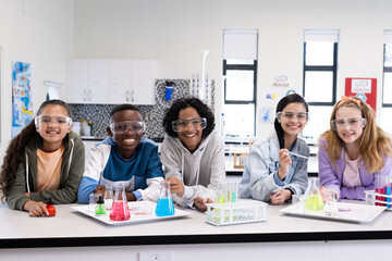 In school, diverse students conducting science experiment with colorful liquids in classroom