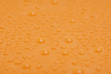 Orange plastic background with water drops. Yellow background.