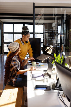 Collaborating on coding project, diverse women focused in modern office