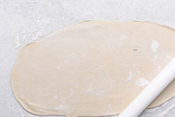 Overhead view of rolled out paratha dough, top view of flaky flatbread dough, process of making paratha