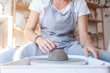 Potter shaping clay on a spinning wheel in a natural light studio