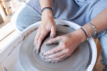 Hands of a ceramic artist shaping clay on pottery wheel