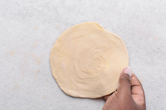 Overhead view of rolled out paratha dough, top view of flaky flatbread dough, process of making paratha