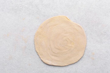Overhead view of rolled out paratha dough, top view of flaky flatbread dough, process of making paratha