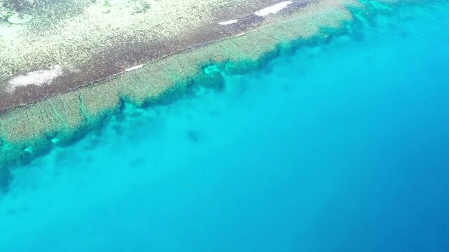 Vertical view from scenic coral reef to tropical resort island and sky in Fiji &ndash; aerial 4k.
