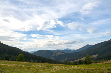 Picturesque panoramic view featuring grassy hills, dense forests, and distant mountains under a...