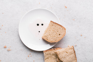 Overhead view of sliced homemade artisan bread with a plate of oil and balsamic vinegar on a white...