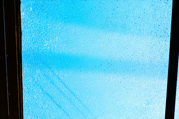Fractured vibrant blue pane of glass, showcasing a textured surface. Cracked glass revealing a...