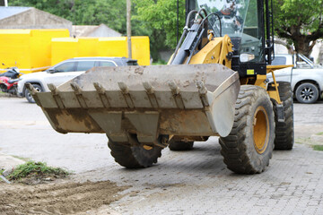 
Man driving an excavator in an urban area with cars in the background