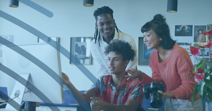 Pointing creative team examining project at office desk using graphic tablet, with DSLR camera