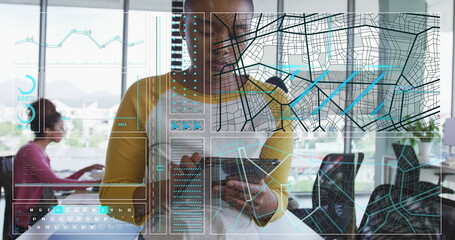 Person in mustard shirt using tablet, interacting with holographic map alongside coworker in office