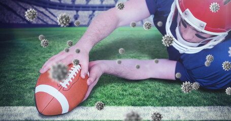 Diving football player in red helmet, jersey placing ball on stadium goal line, virus particles