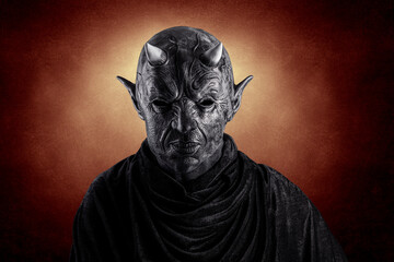 Portrait of a bad devil with horns on head over dark fiery background