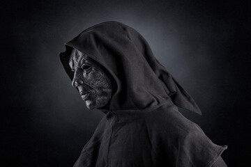 Scary figure with hooded cloak over dark misty background with clipping path