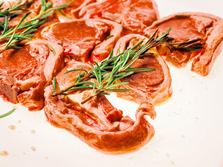 Premium quality marinated lamb loin chops and rosemary herb on white background. Uncooked raw meat...