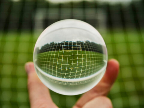 Football or soccer goal posts in glass ball which is hold by a someone hand. Forecasting sport results in popular world sport. Betting on club and national teams concept. Selective focus.