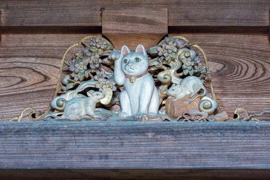 An ancient wood carving depicting a Japanese lucky cat or Maneki-Neko surrounded by mice as a decoration on a wooden pagoda at Gotokuji temple in Tokyo, Japan