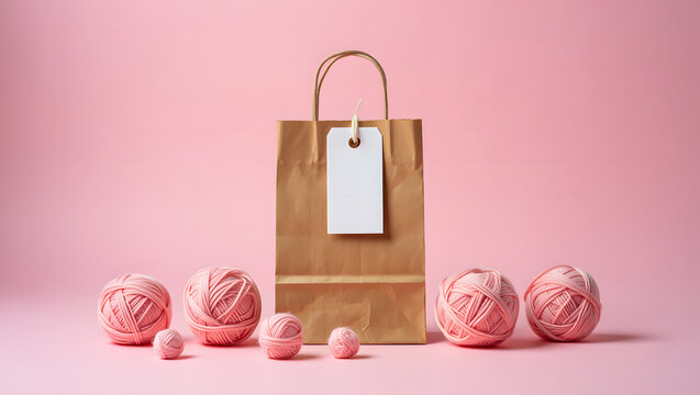Pink yarn balls and brown paper shopping bag on pink background