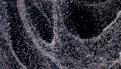 Close-up view of bubbles rising in liquid during a dynamic movement in a dark environment