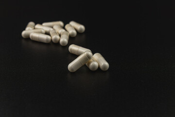 Pills scattered on a dark surface highlighting their texture