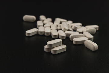 White tablets scattered on a dark surface in a close-up view