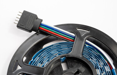 Closeup of an RGB RGBWW LED lights strip with a 5 pin connector and color coded wires on reel, detailed view of smart lighting technology component for home automation, decoration electronic projects