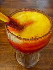 A Mexican mangonada or tangy mango Margarita with a tamarind candy straw.