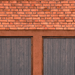 Blue garage doors beneath a brick wall in warm evening light. Architectural texture and shadowed...