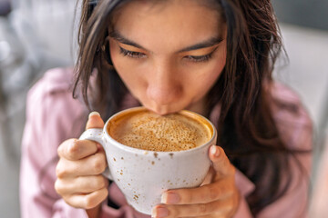 Young freelancer woman drinking cappuccino in coffee shop