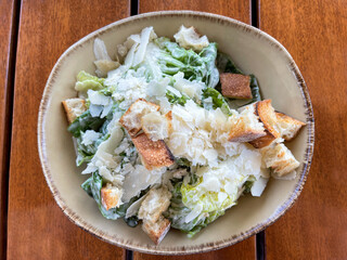 Top view of a Caesar salad with crunchy croutons and freshly shredded parmesan cheese.