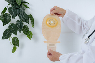 One elderly doctor holds a new colostomy bag.