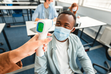 Teacher using digital medical contactless infrared electronic thermometer, measuring and checking...