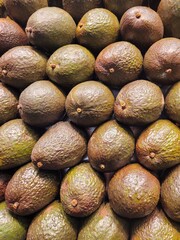 Stacked avocados forming a fresh and vibrant background.The image highlights the natural texture and earthy tones of the fruit, ideal for healthy food concepts, packaging design, or organic lifestyle.