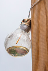 A string of LED bulbs hanging from a wooden post