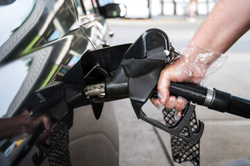 Man driver hand refilling the car with fuel at the gas petrol station. 