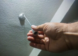 Hand pulling a light porcelain chain light switch attached to the ceiling