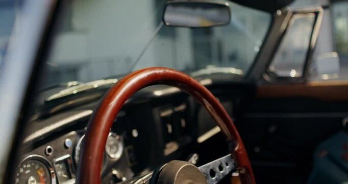 A woman puts her hand on the steering wheel of a retro car, preparing for a trip. Close-up of her hand, unrecognizable person