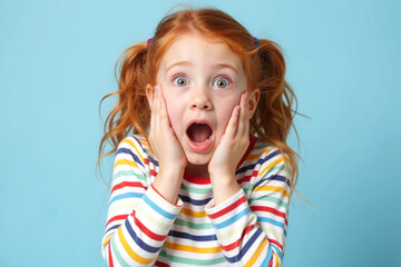 A young girl with red hair in pigtails and a colorful striped shirt looks surprised with her hands on her cheeks.