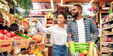Black Family On Grocery Shopping In Supermarket. Happy African Couple Buying Organic Vegetabels And...