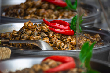 a large pile of prepared snail meat in a metal container