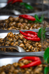 a large pile of prepared snail meat in a metal container